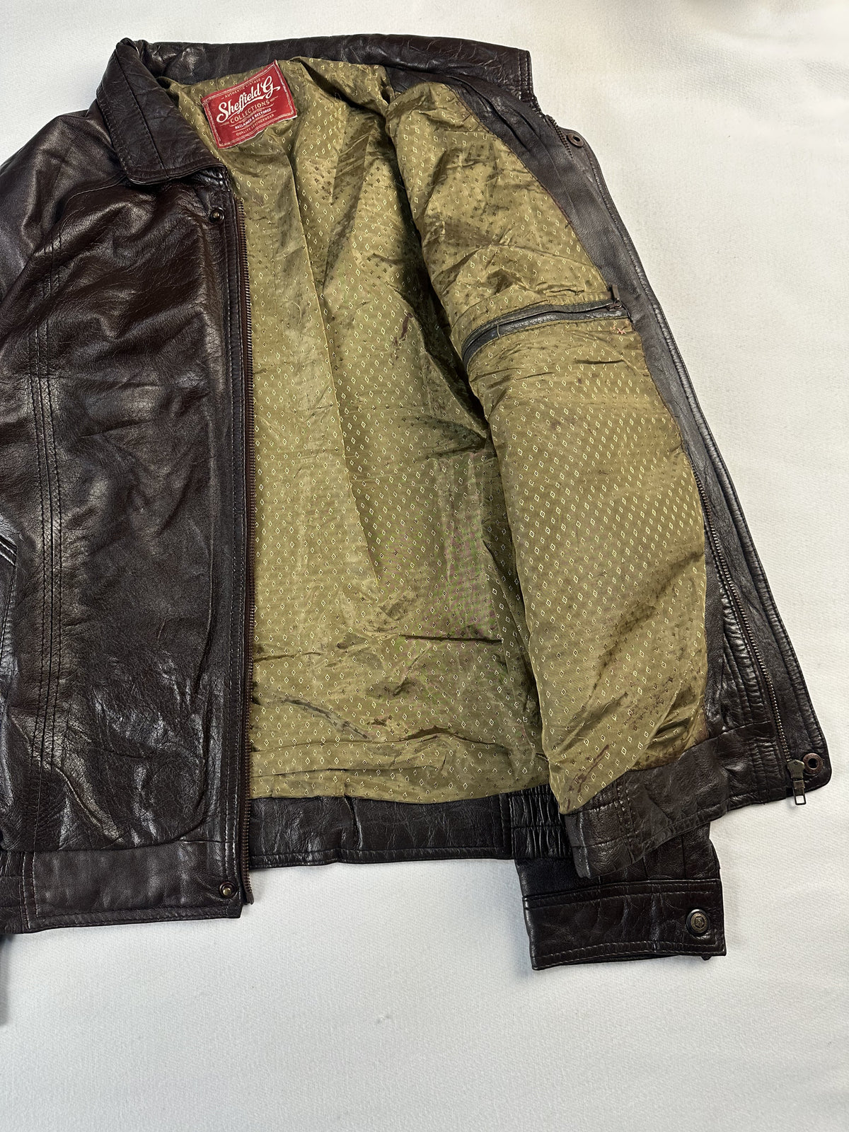 The bomber held open to show the full olive lining and the elasticated hem