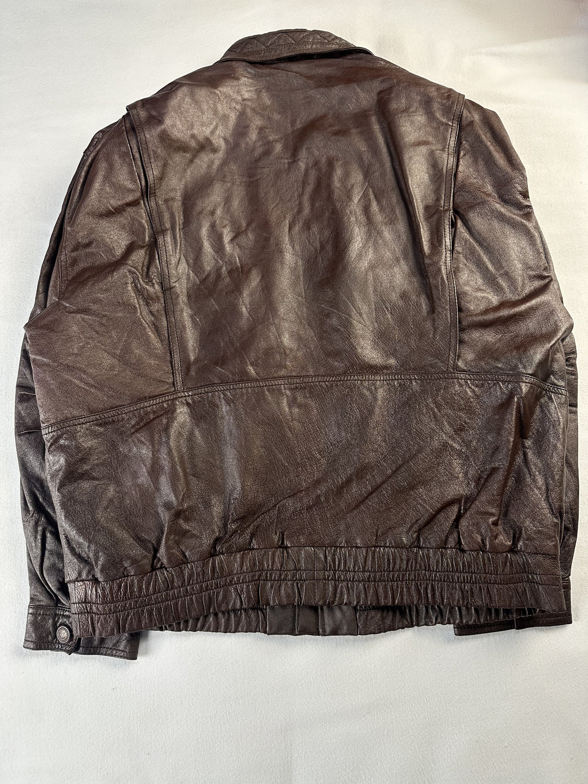 Rear view of the XL brown jacket laid flat with its elasticated waistband and stud tab