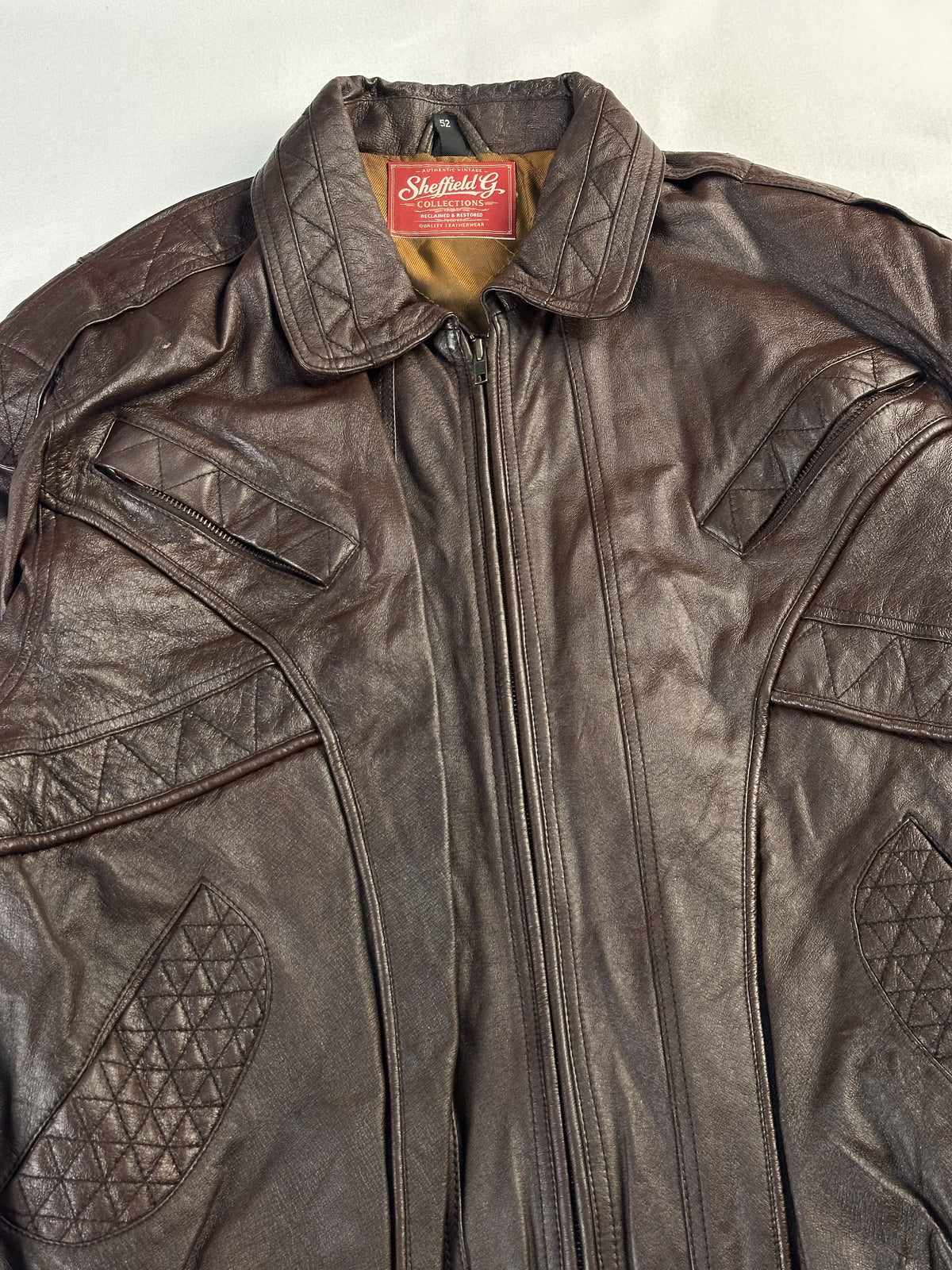 Close view of the point collar, neck label and quilted chest panels at the zip