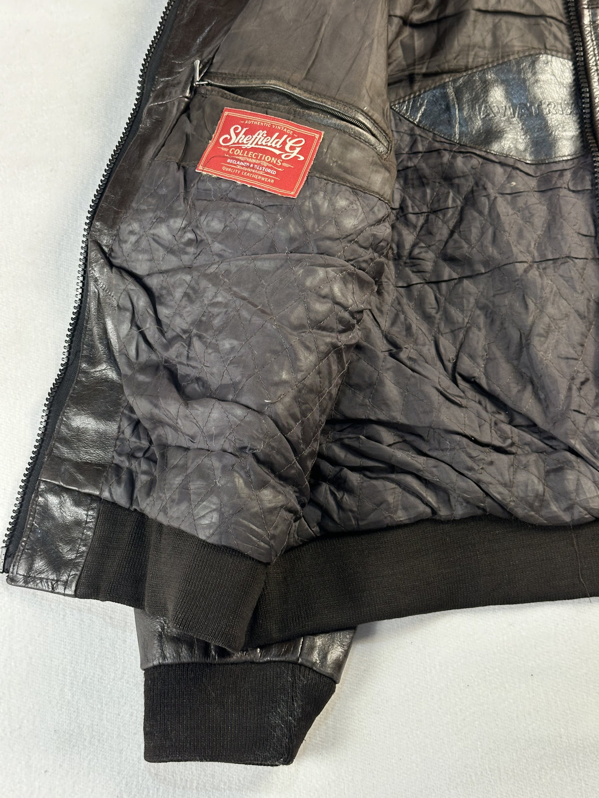 Dark lining with a zipped interior pocket and label inside the brown flight jacket