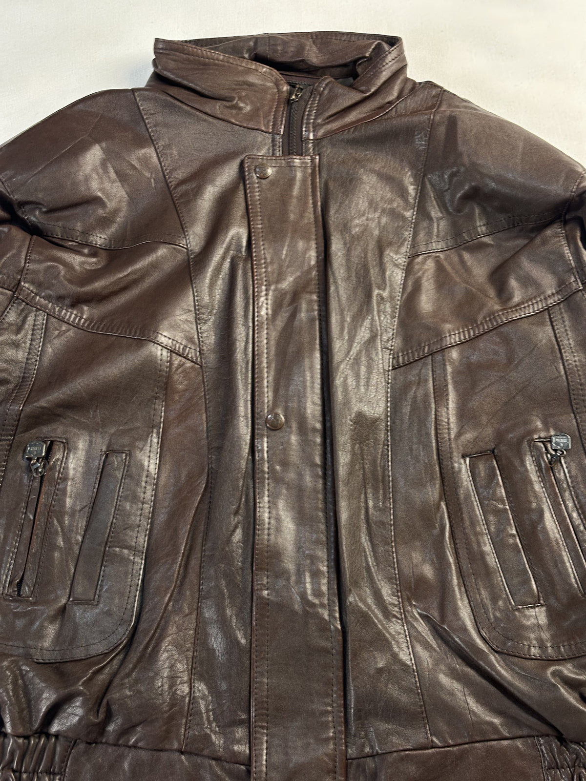 Close view of the stand collar, centre zip and the tops of both zipped patch pockets