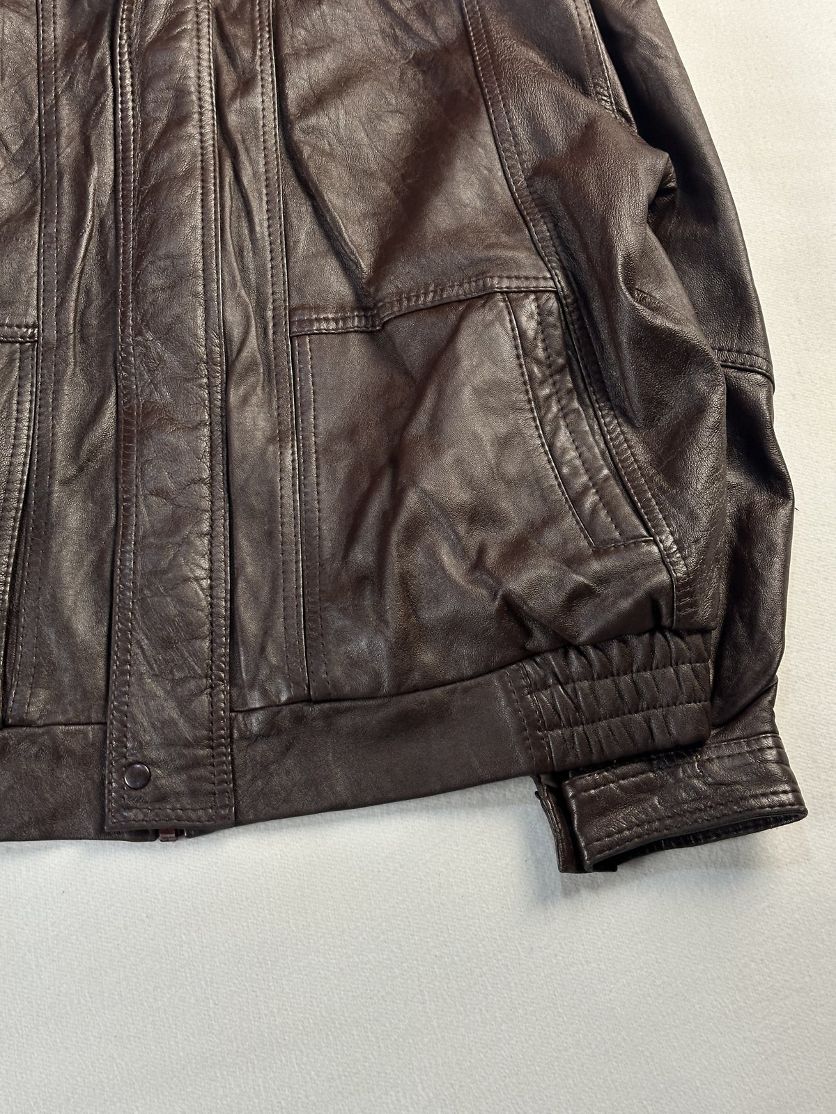 Right side pocket, press stud placket and elasticated cuff on the brown leather jacket