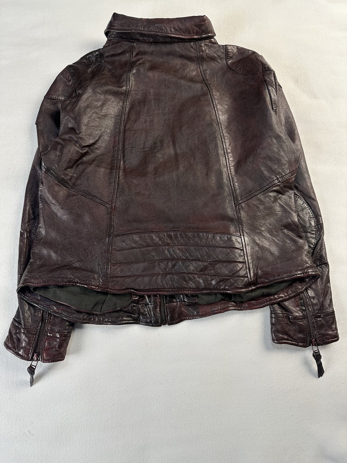 Back of the size M brown jacket laid flat with drawstring cords hanging at the hem