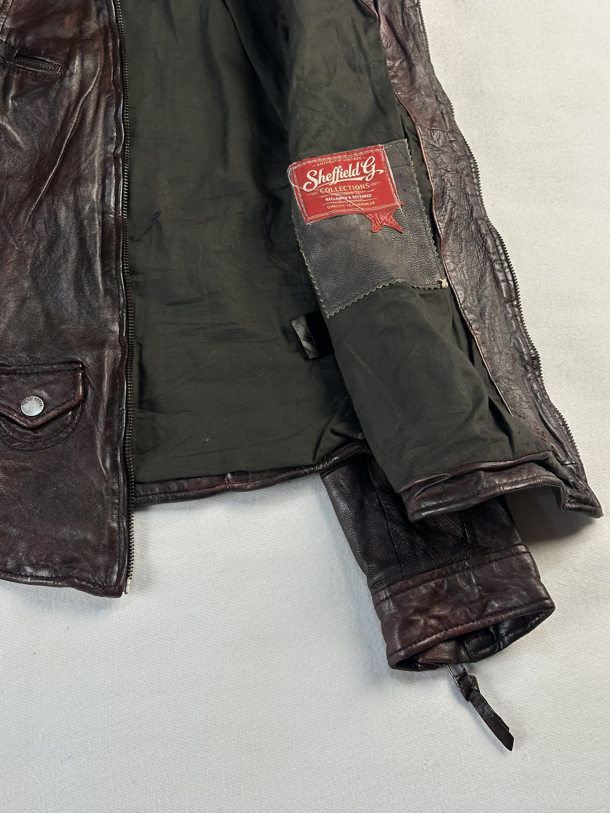 Dark olive lining and inner neck label seen inside the opened brown jacket