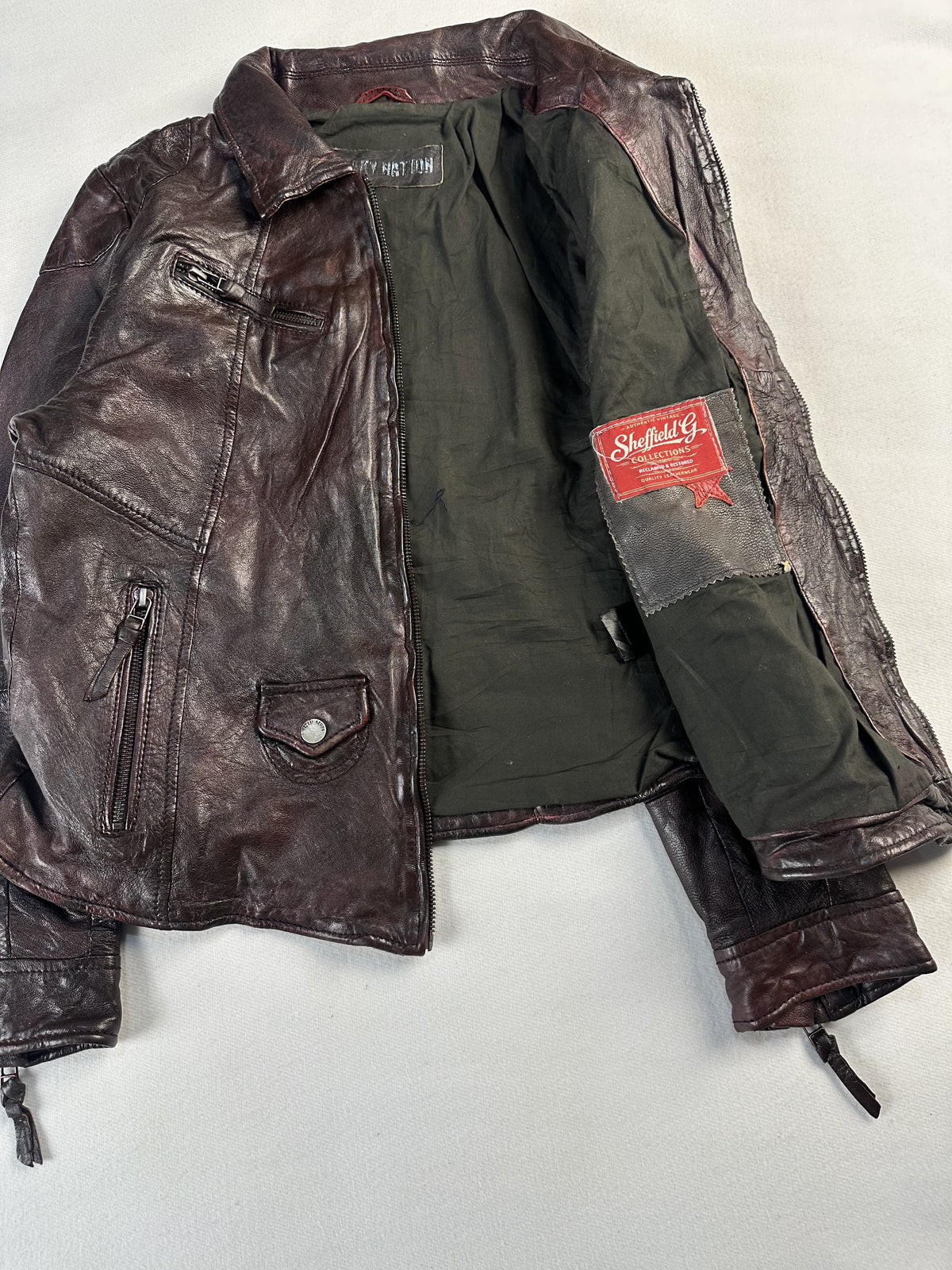 The jacket laid open flat to show the full olive lining and the front zip