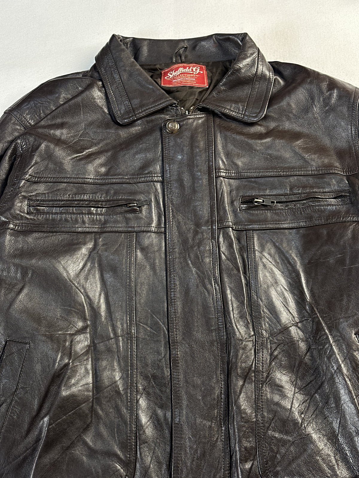 Close view of the point collar, neck label and press stud above the chest zips