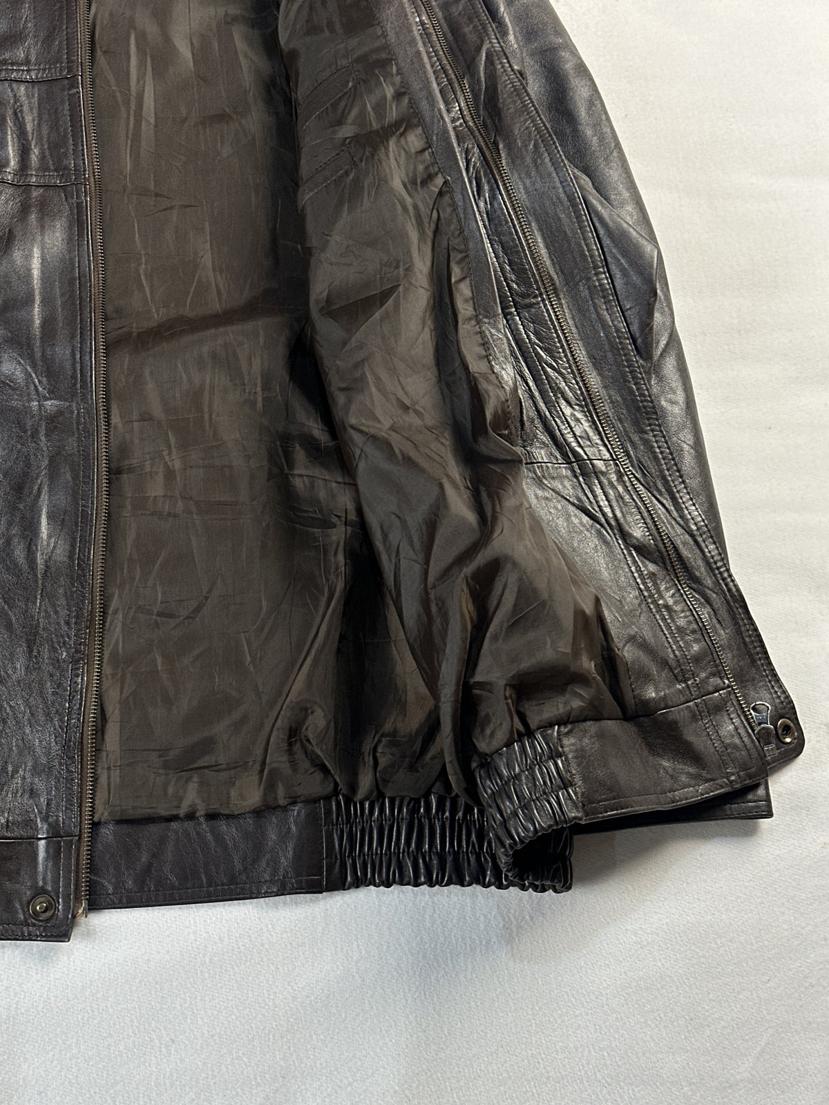 Plain dark lining inside the brown jacket, held open beside the elasticated cuff