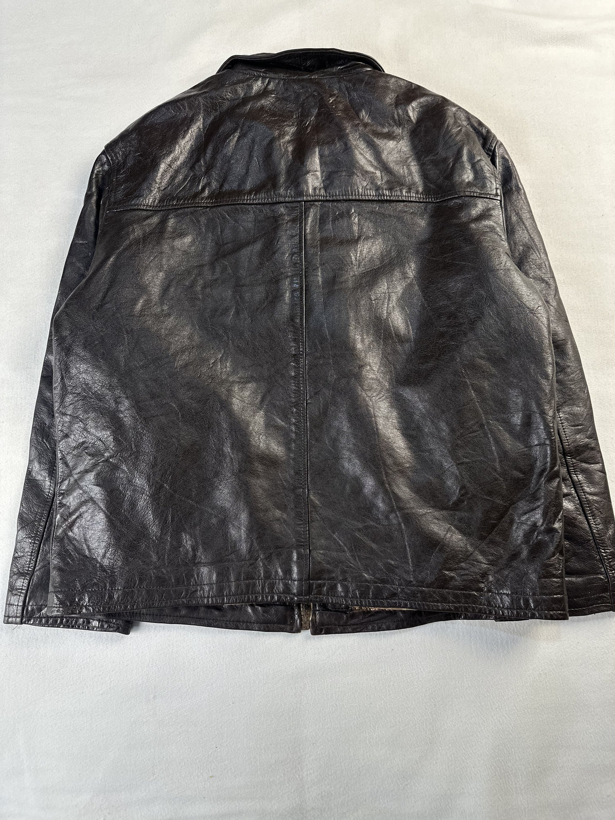 Rear view of the XL brown leather jacket laid flat with its plain back panel