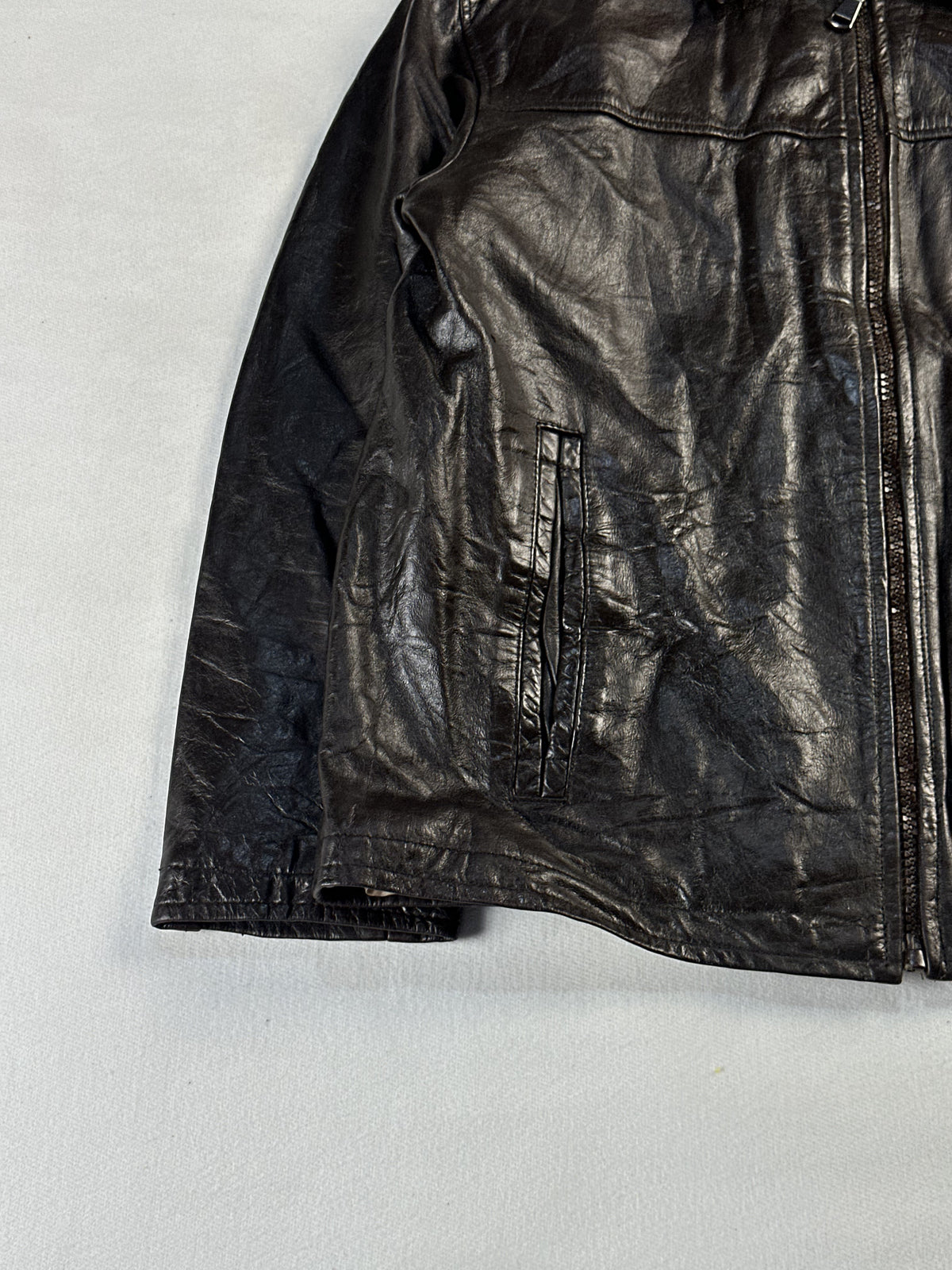 Lower front corner showing a welt hand pocket, straight hem and cuff