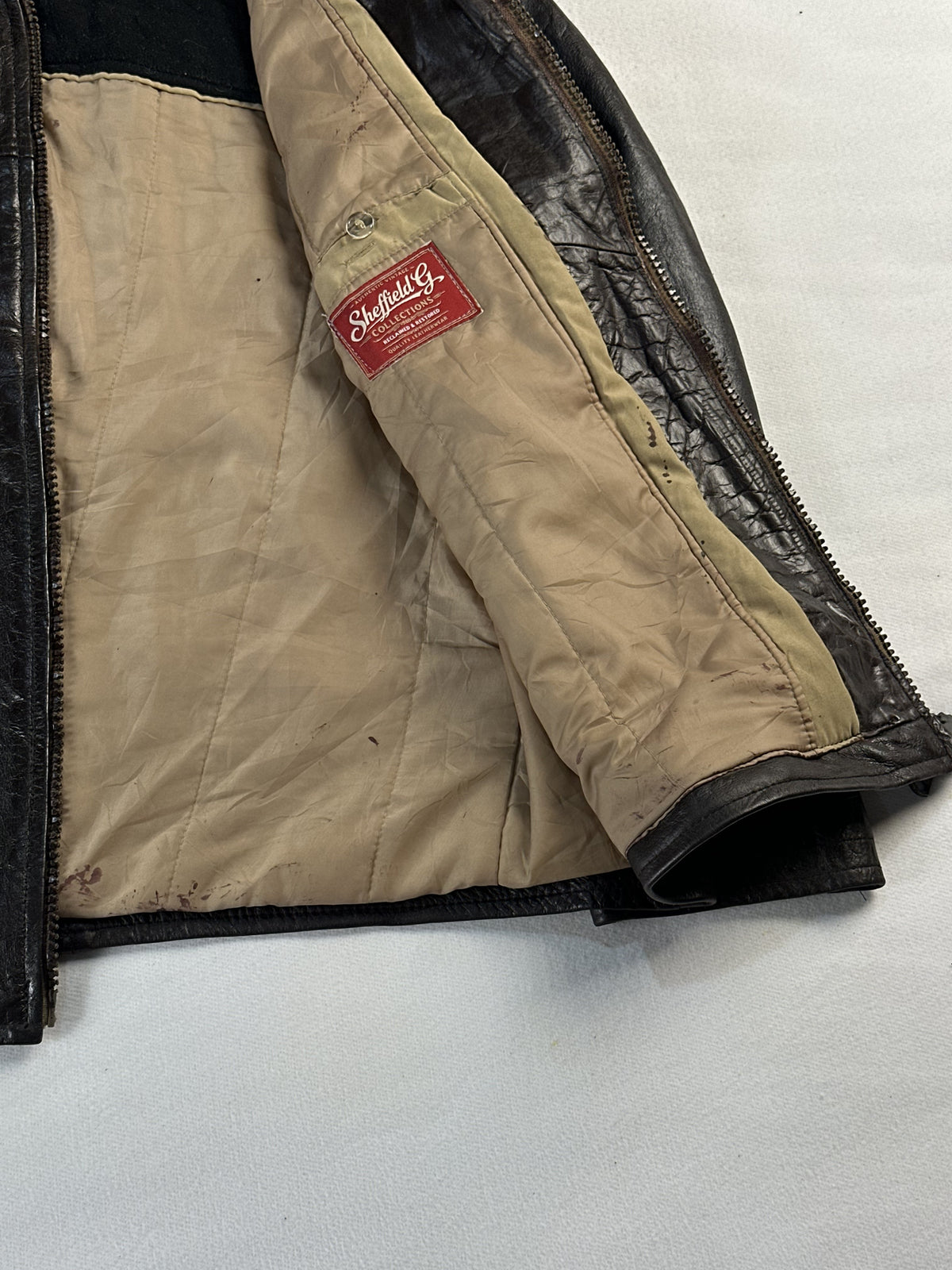 Tan cotton lining inside the jacket, shown close against the dark leather edge