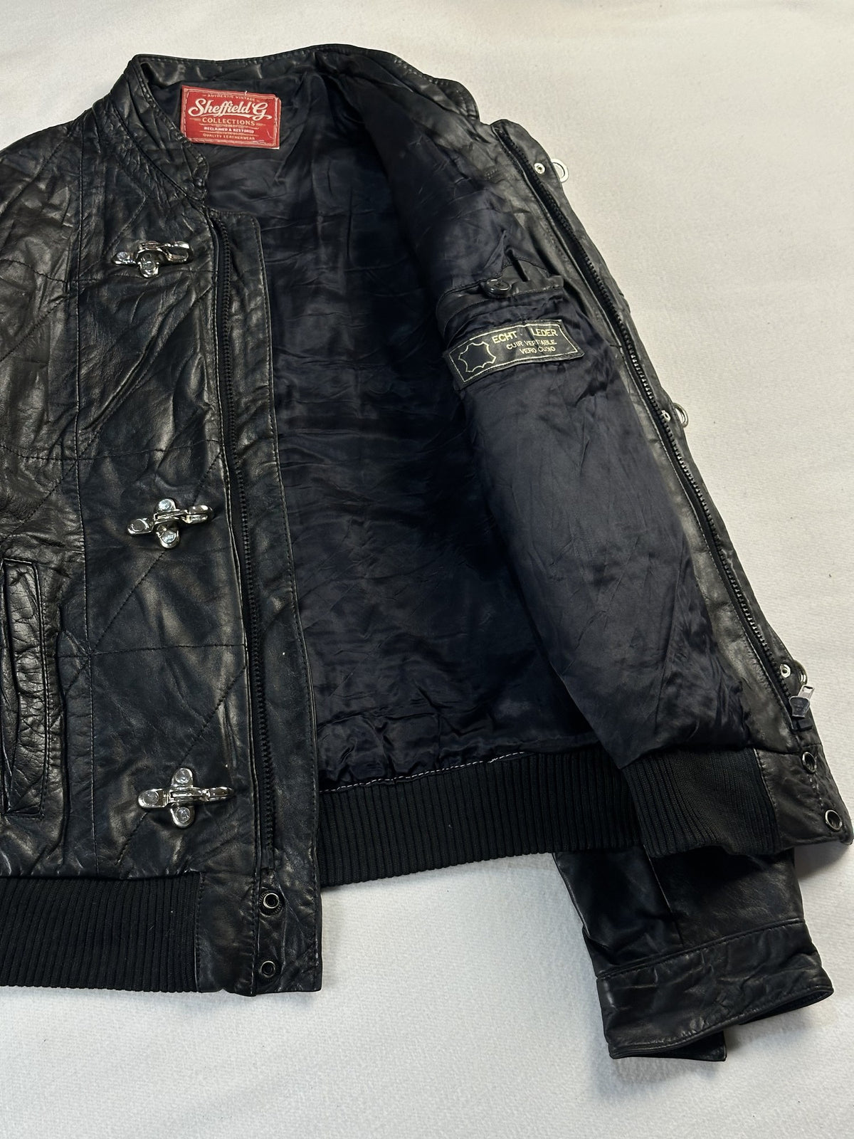 Black leather bomber jacket, size S - cuff and hem detail.