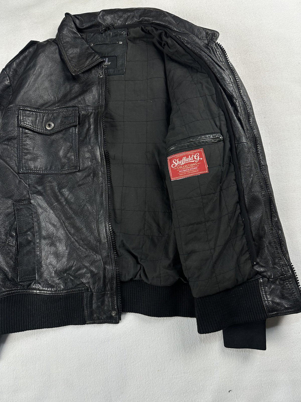 Black leather bomber jacket, size M - cuff and hem detail.