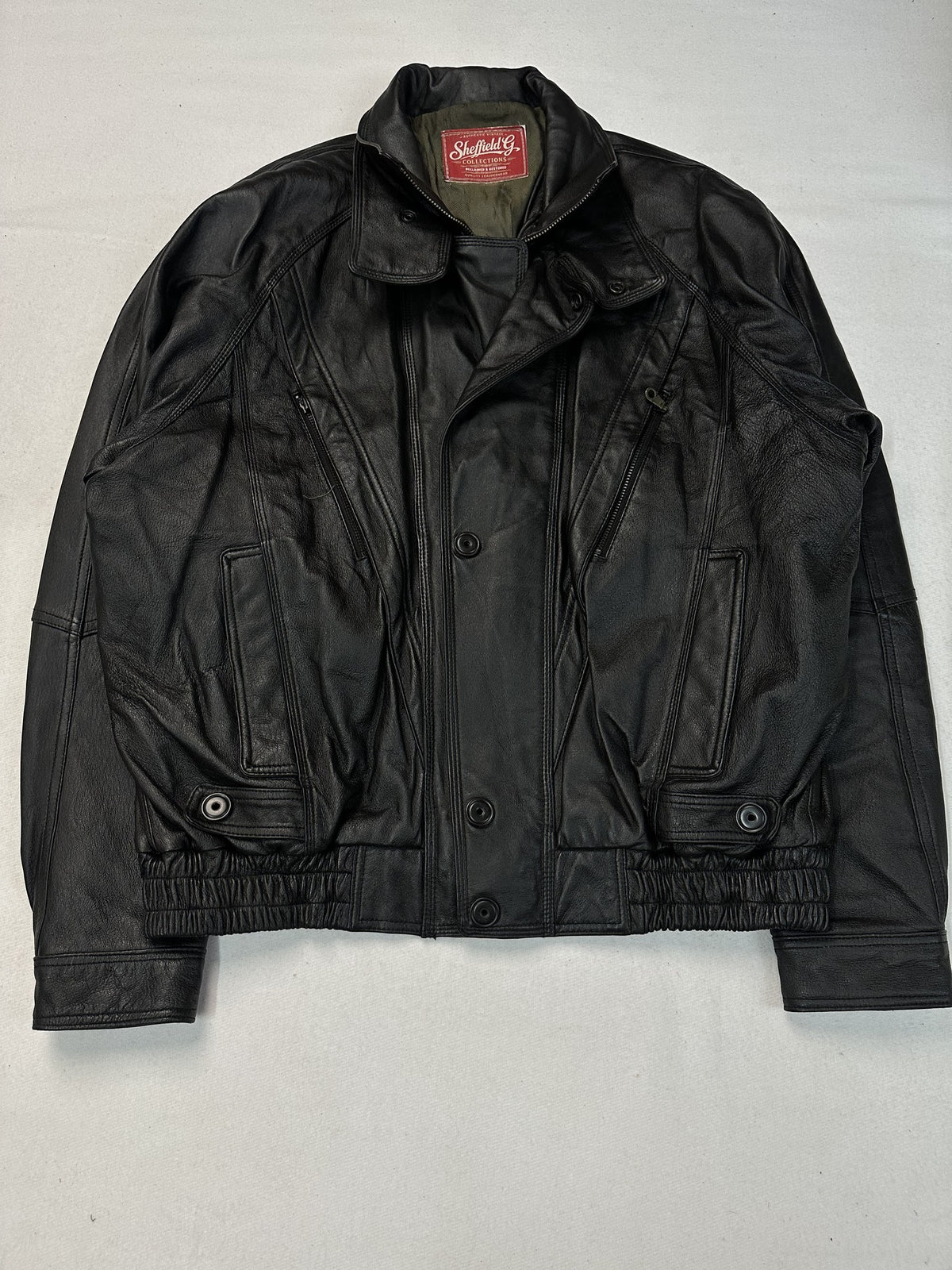 Four snap flap pockets across the front of the black leather vintage jacket.