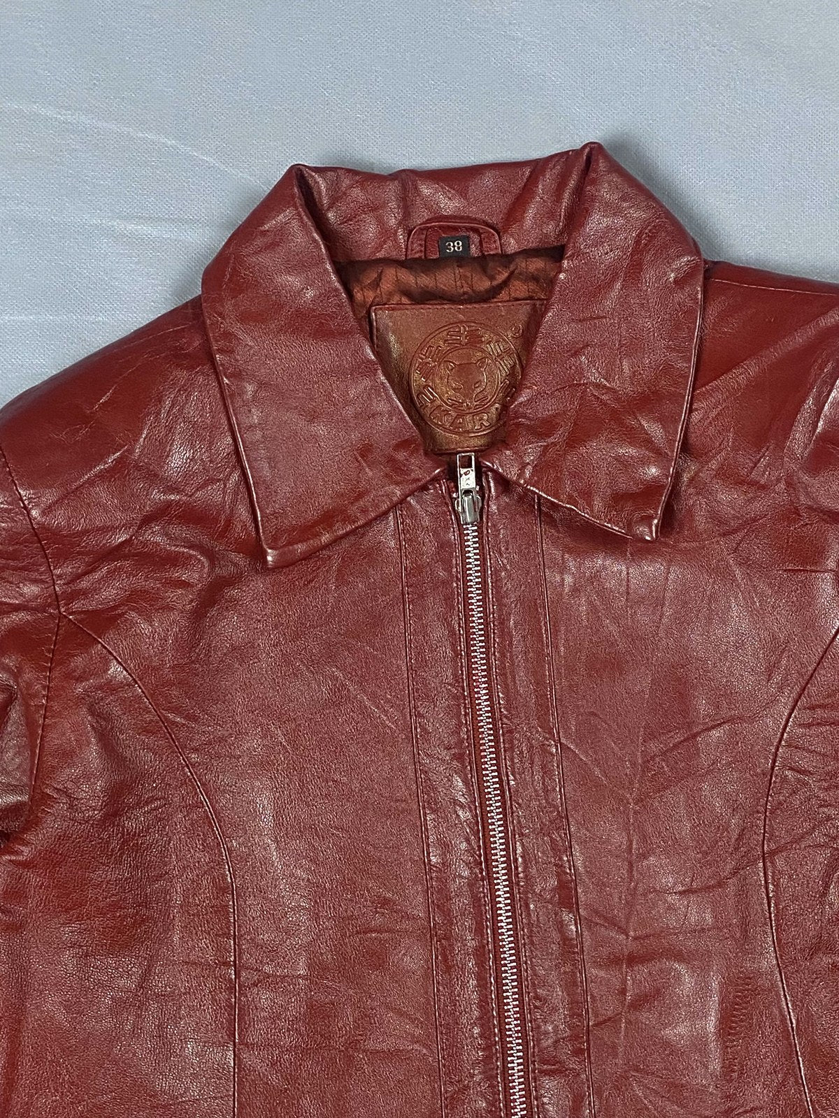 Pointed shirt collar and centre zip on the burgundy leather biker jacket