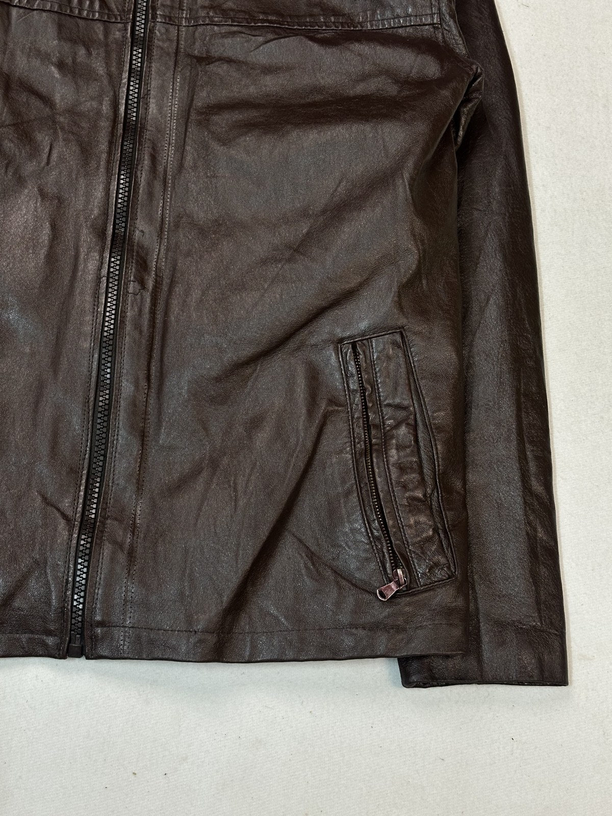 Close look at the zip pull and concealed pocket opening on the burgundy biker jacket