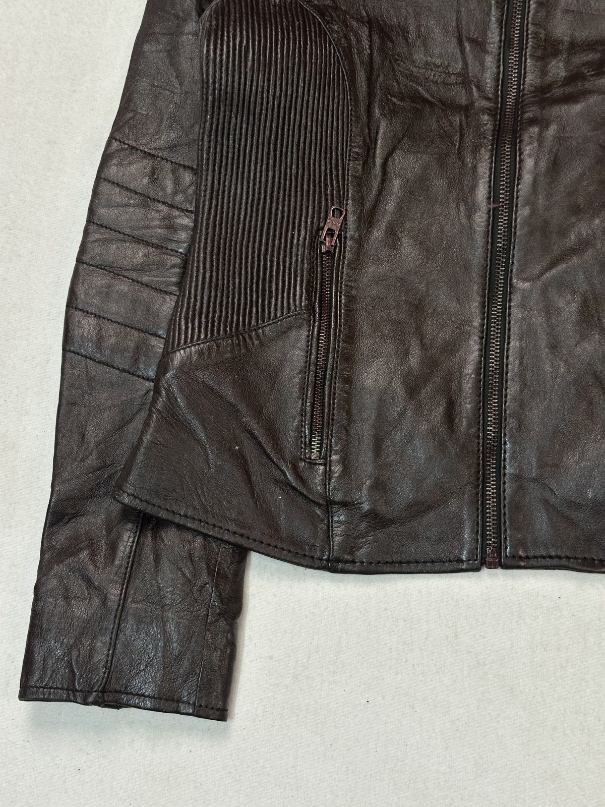 The size S burgundy biker jacket seen at an angle with the front zip and quilted panel in view