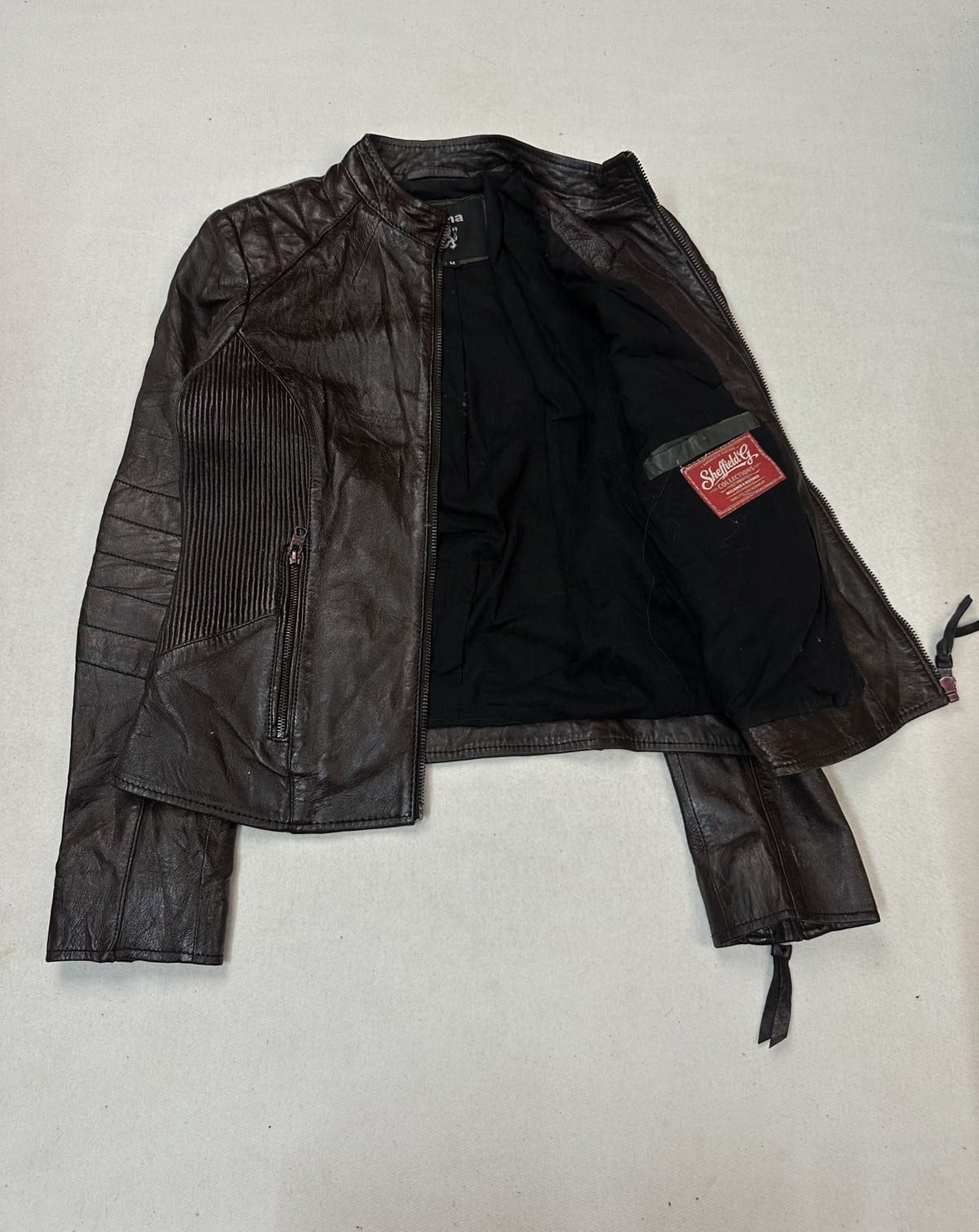 Lining of the small burgundy biker jacket seen through the opened front of the garment