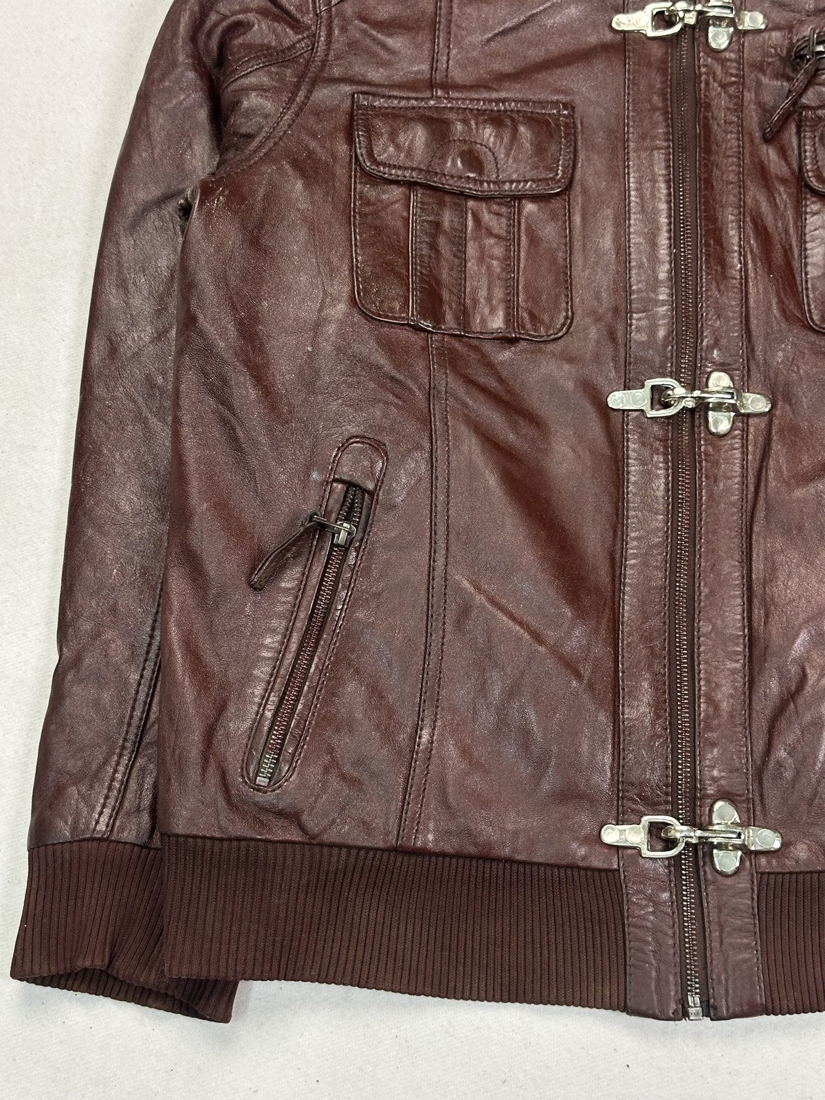 Collar and uppermost brass clasp on the burgundy biker jacket, shot close