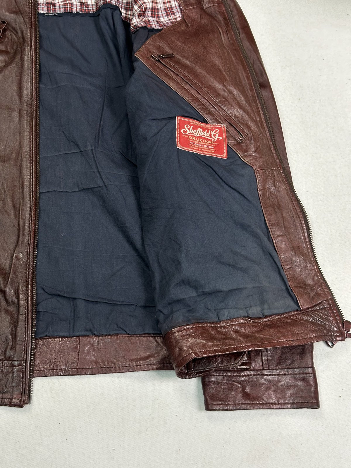 Navy lining inside the burgundy leather biker jacket, held open to show the interior