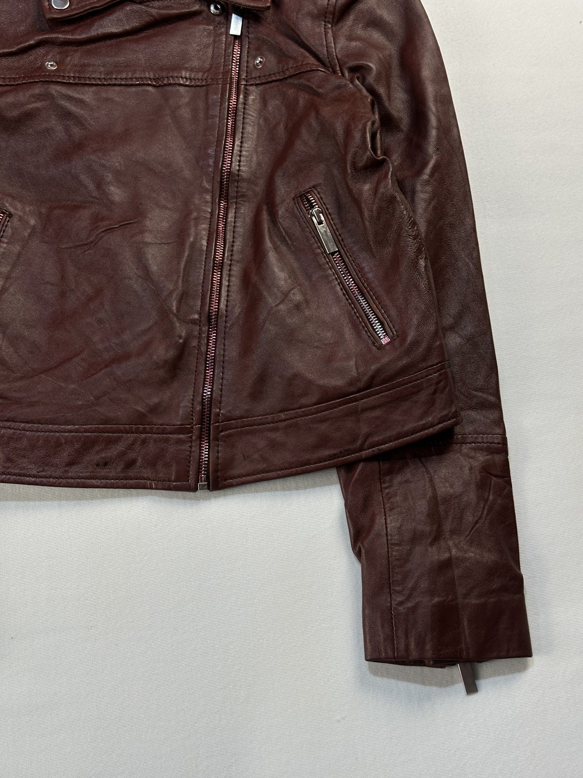 Close view of the leather grain and stitching on the burgundy jacket