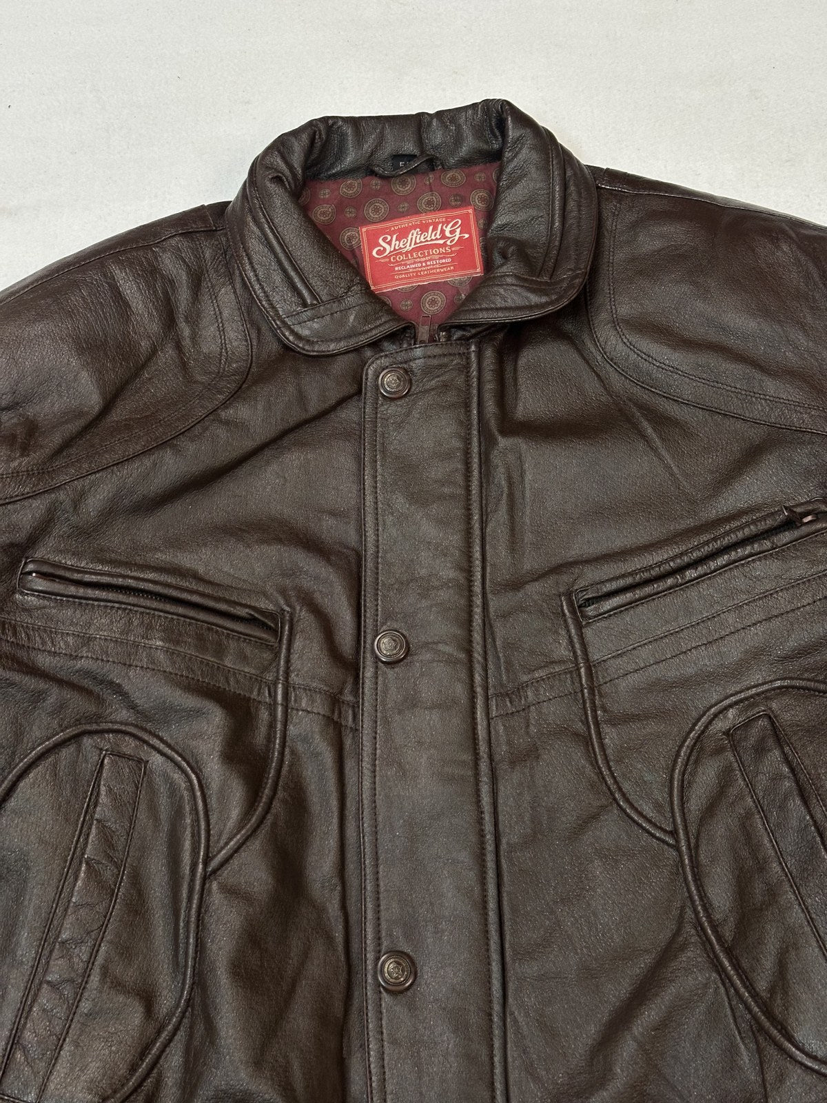 Close view of the flat shirt collar on the burgundy bomber jacket