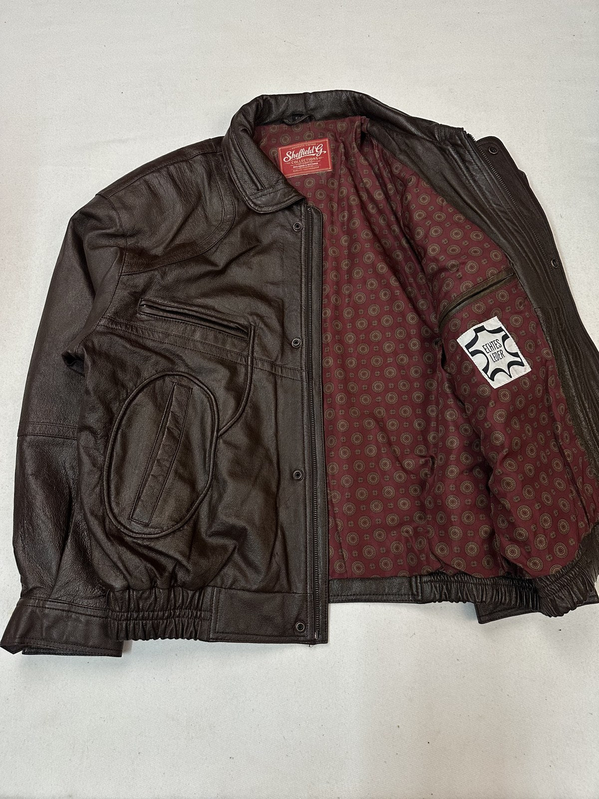 Detail of a hip flap pocket and its stitching on the burgundy XXL bomber jacket