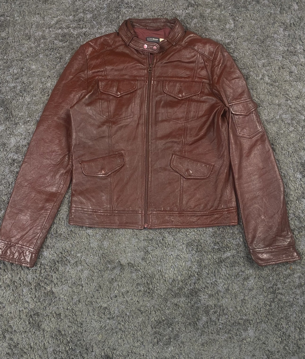 Snap-stud collar fastening at the neck of the burgundy bomber jacket
