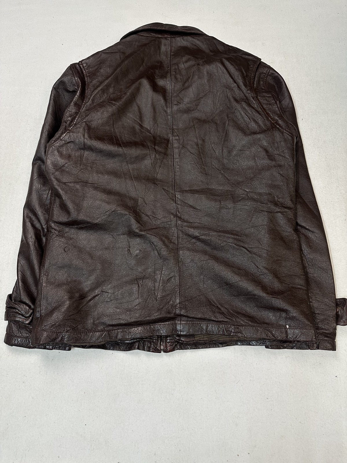 The unbroken back panel of this large burgundy bomber jacket, shown flat