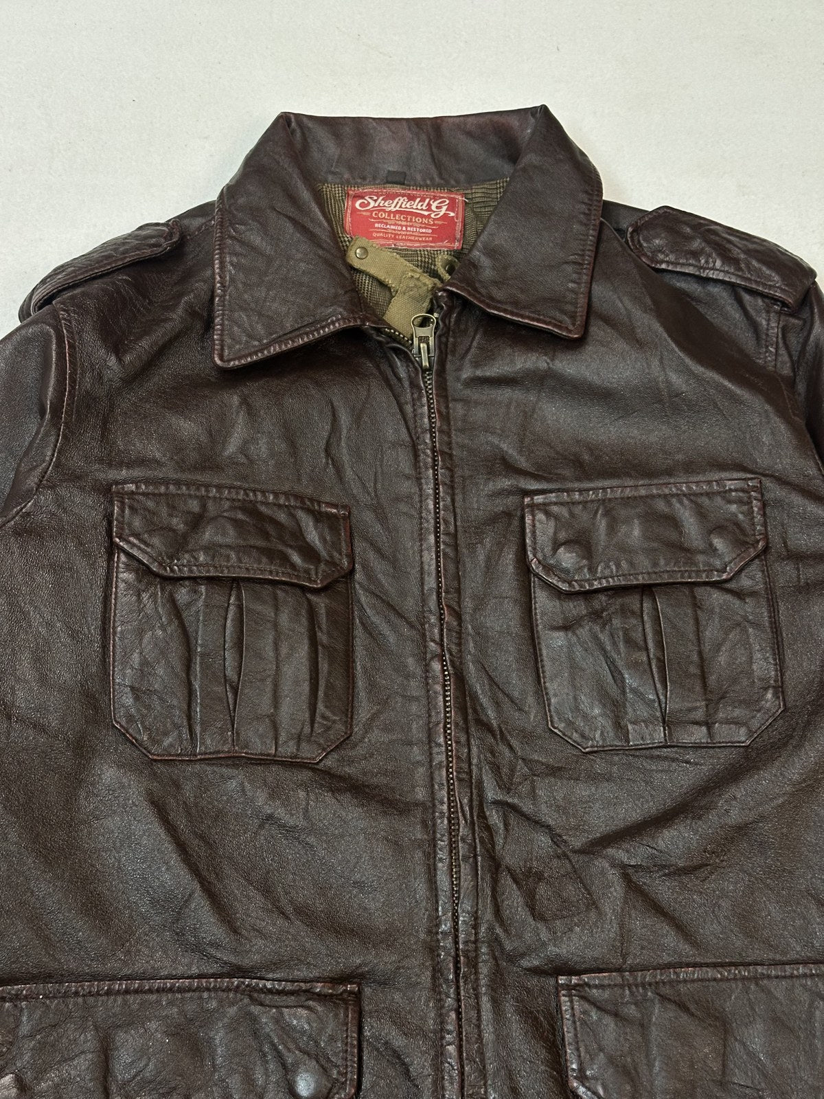 Size L burgundy leather bomber jacket viewed front on, twin chest flap pockets either side of the zip