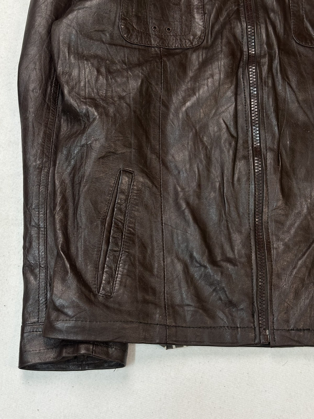 The shirt collar and upper zip of this plain burgundy leather jacket in close up