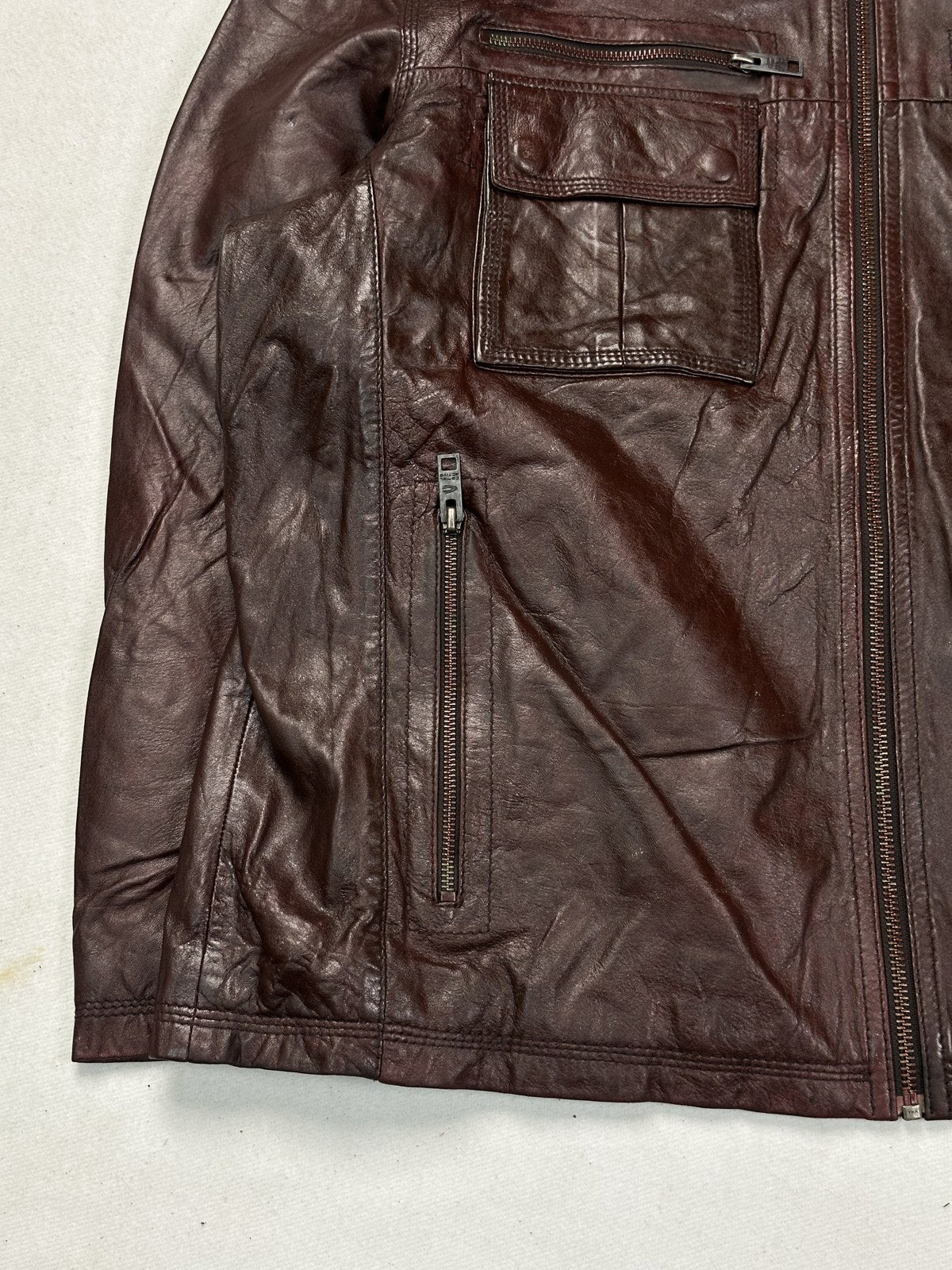 The soft shirt collar of the four pocket burgundy bomber jacket, seen close up