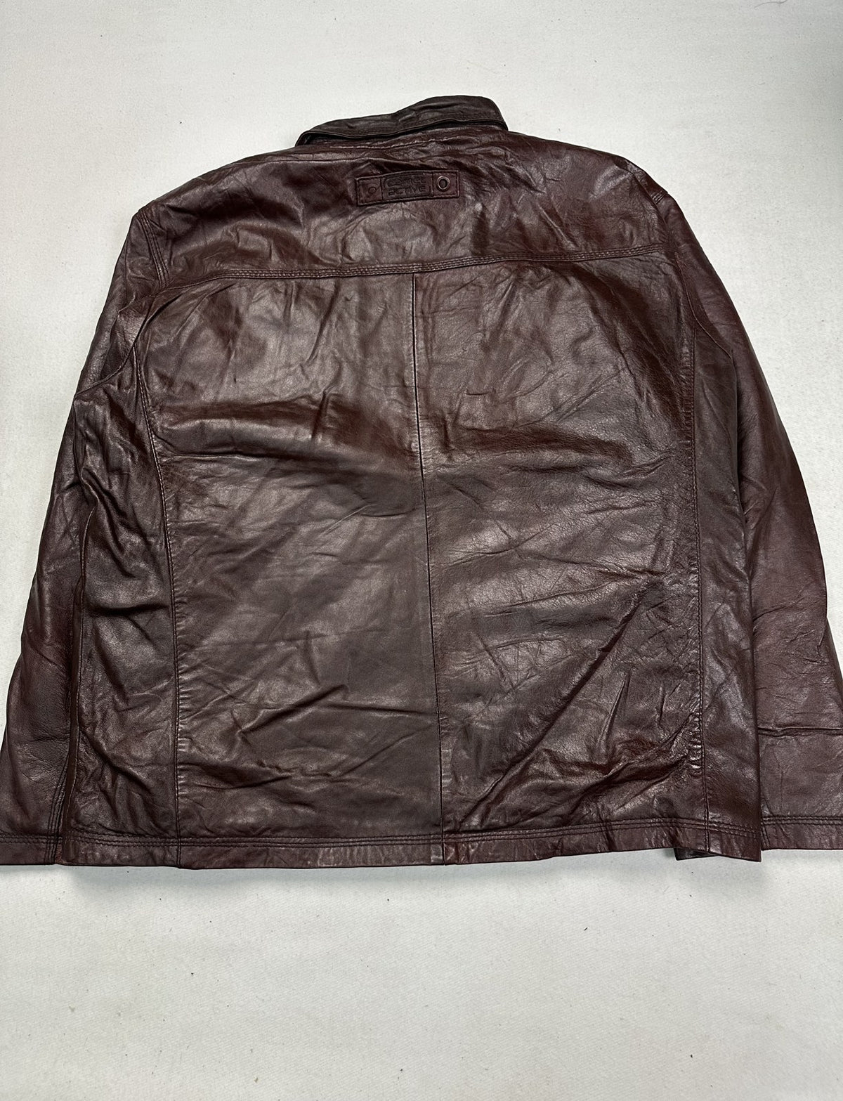 Close view of one flap pocket and its stitching on the burgundy bomber jacket