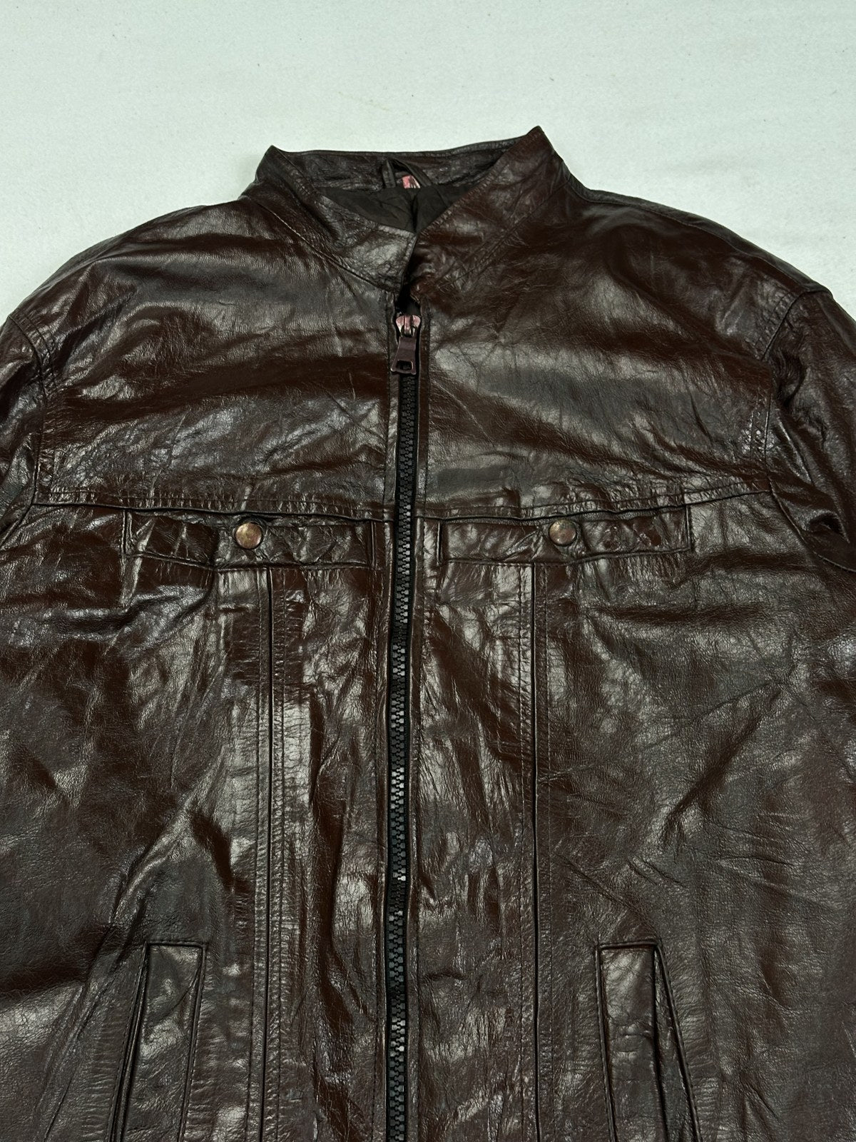 Detail of a front panel seam and the leather surface on the burgundy bomber jacket