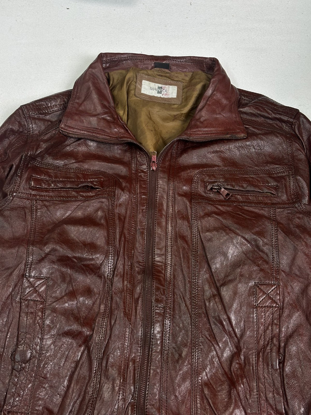 Detail of the front zip tape and rib cuff on the size L burgundy bomber jacket