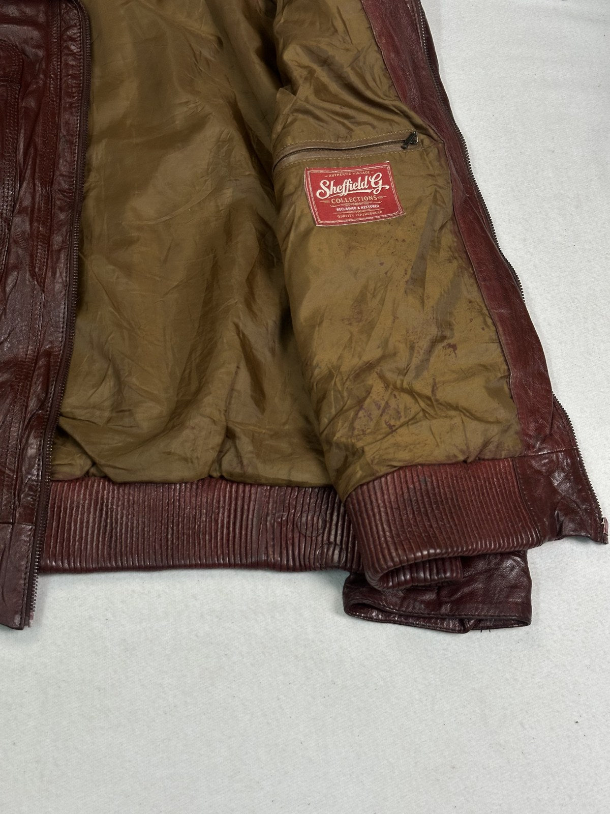 Olive satin lining shown inside the size L burgundy bomber jacket