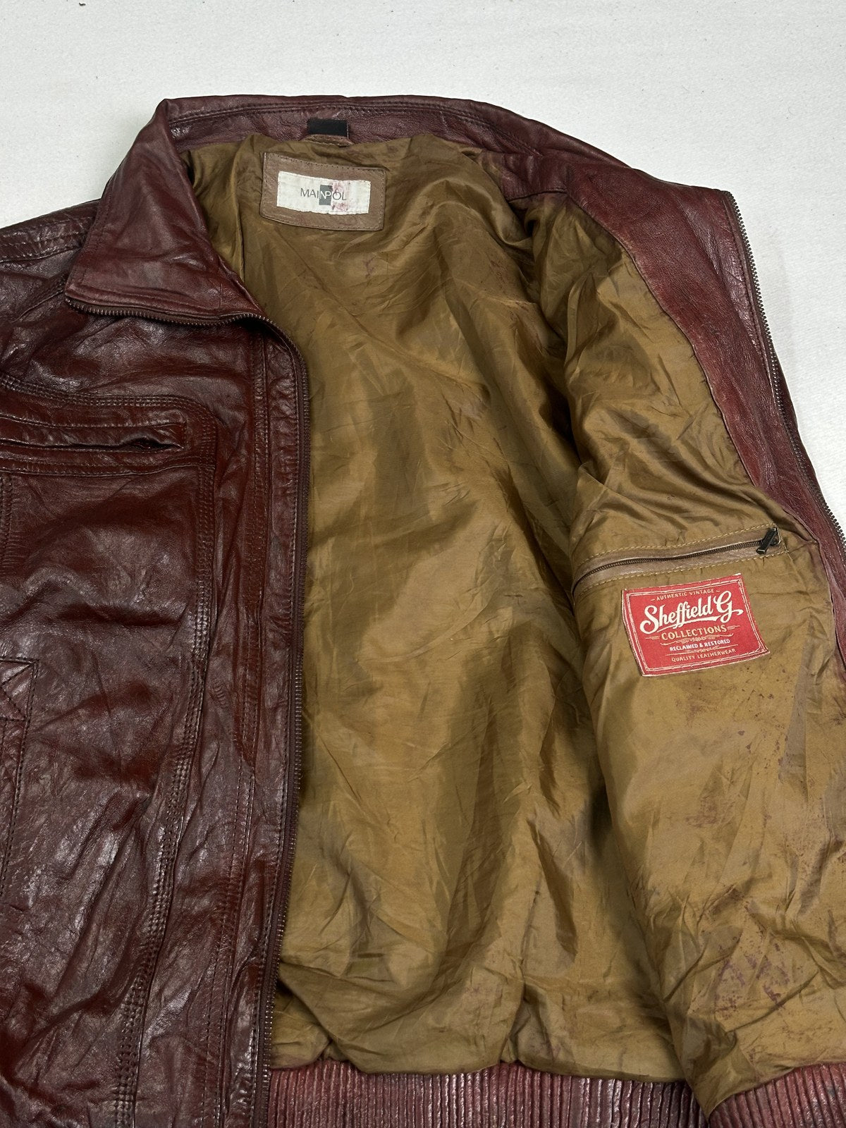 Olive lining inside the size L burgundy bomber jacket, held open