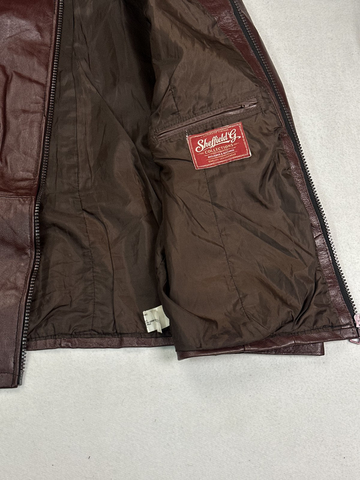 Close range shot of the hem and zip base on the XL burgundy bomber jacket
