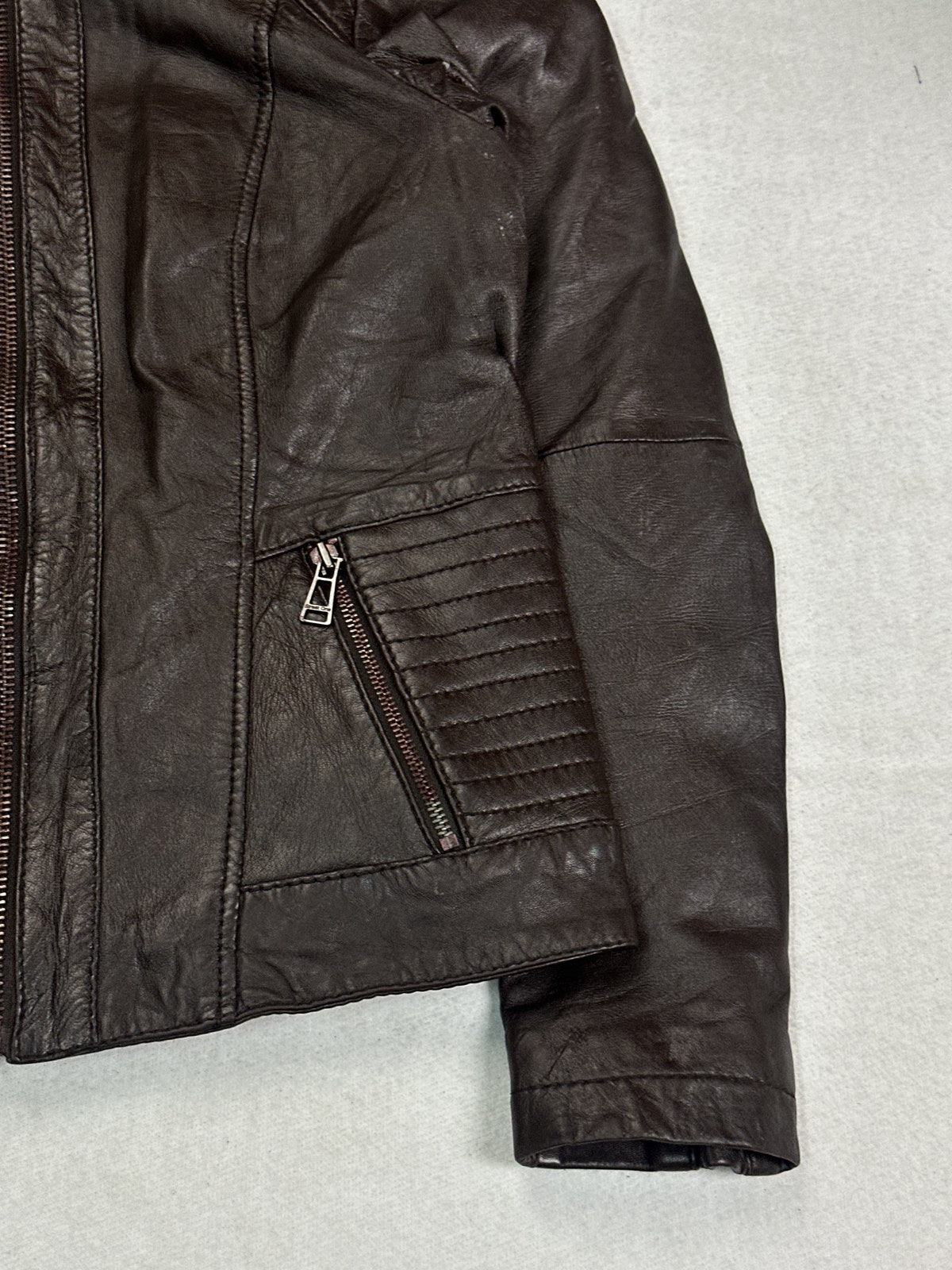 Close view of the leather grain and stitching on the burgundy jacket