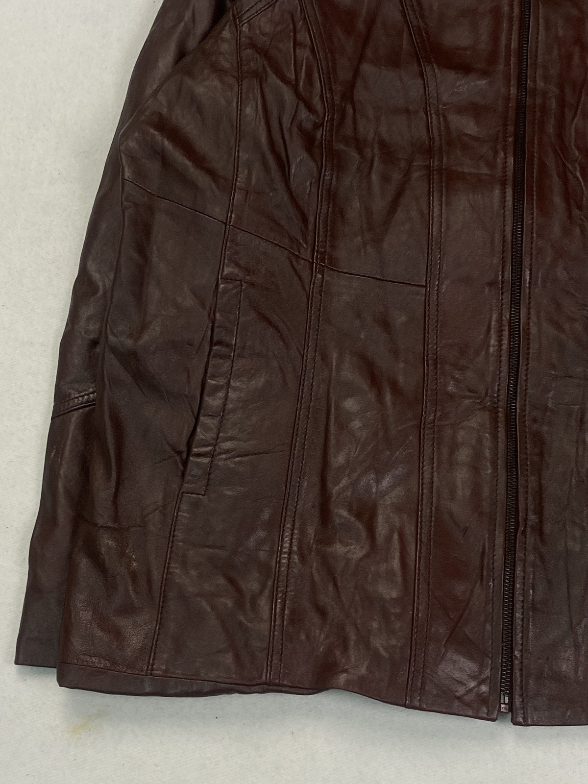 Close view of the leather grain and stitching on the burgundy jacket