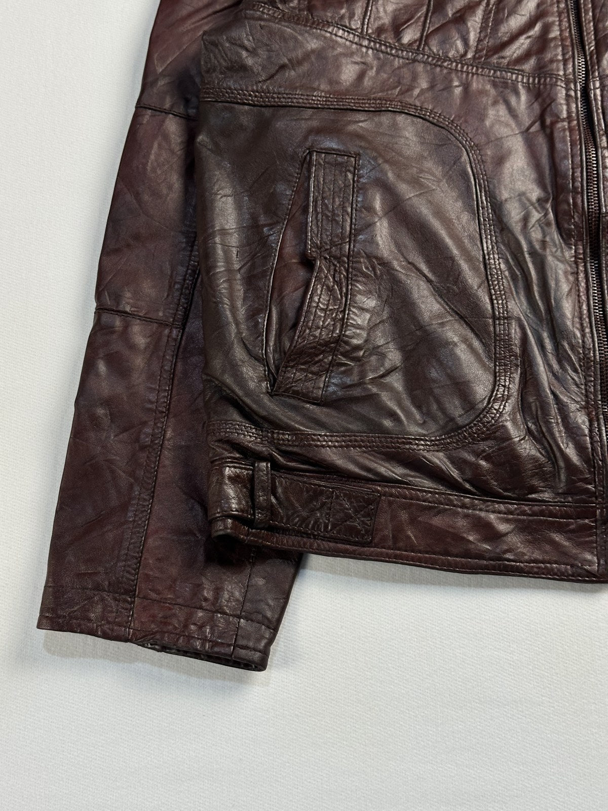 Close view of the leather grain and stitching on the burgundy jacket