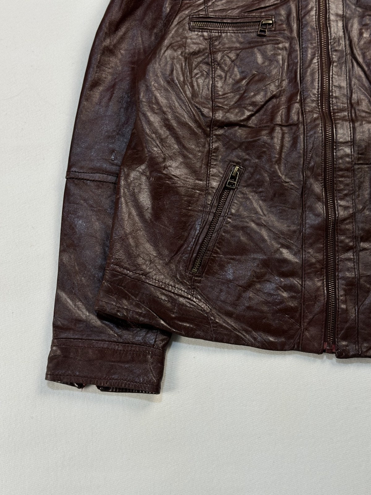 Close view of the zipped cuff and the leather grain on the burgundy jacket