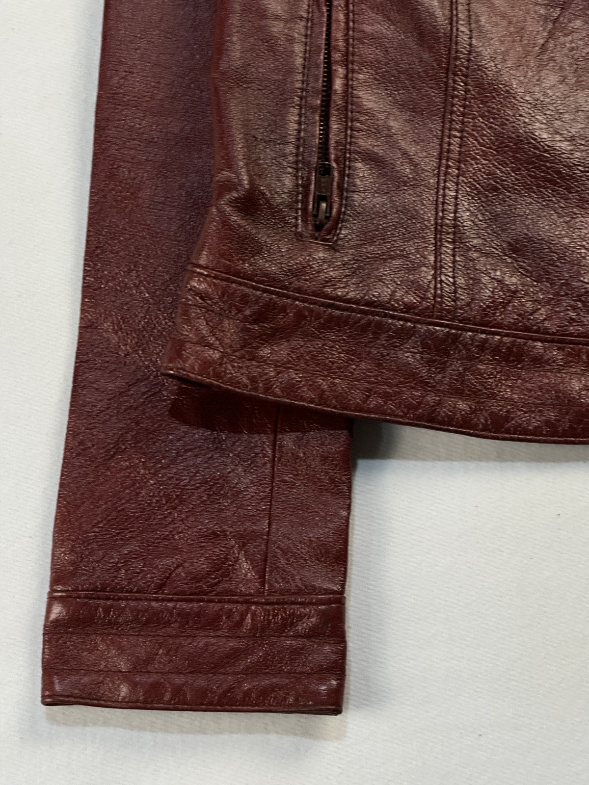 Close view of the leather grain and stitching on the burgundy jacket