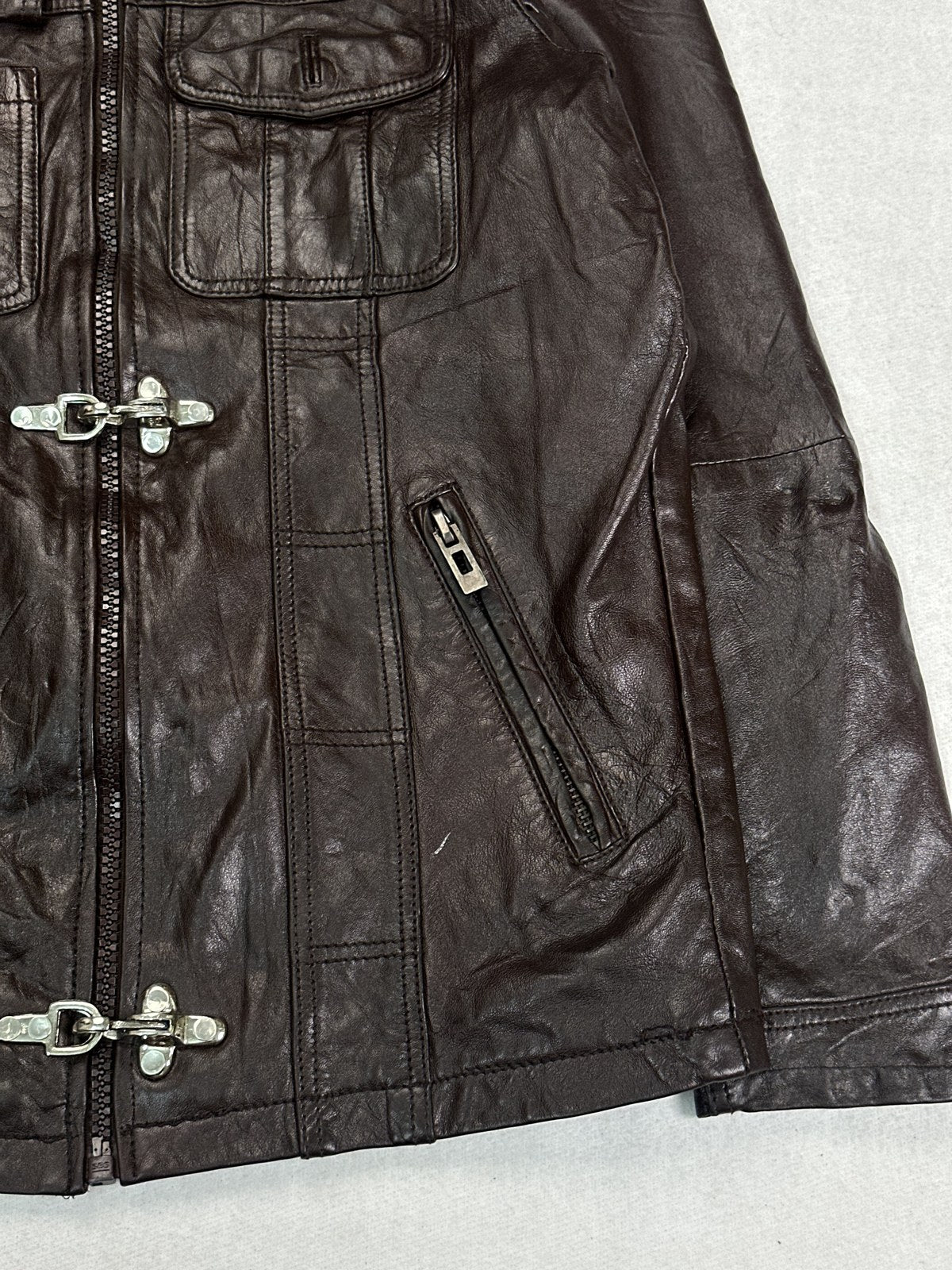 Close view of a dome stud pocket and the leather grain on the burgundy jacket