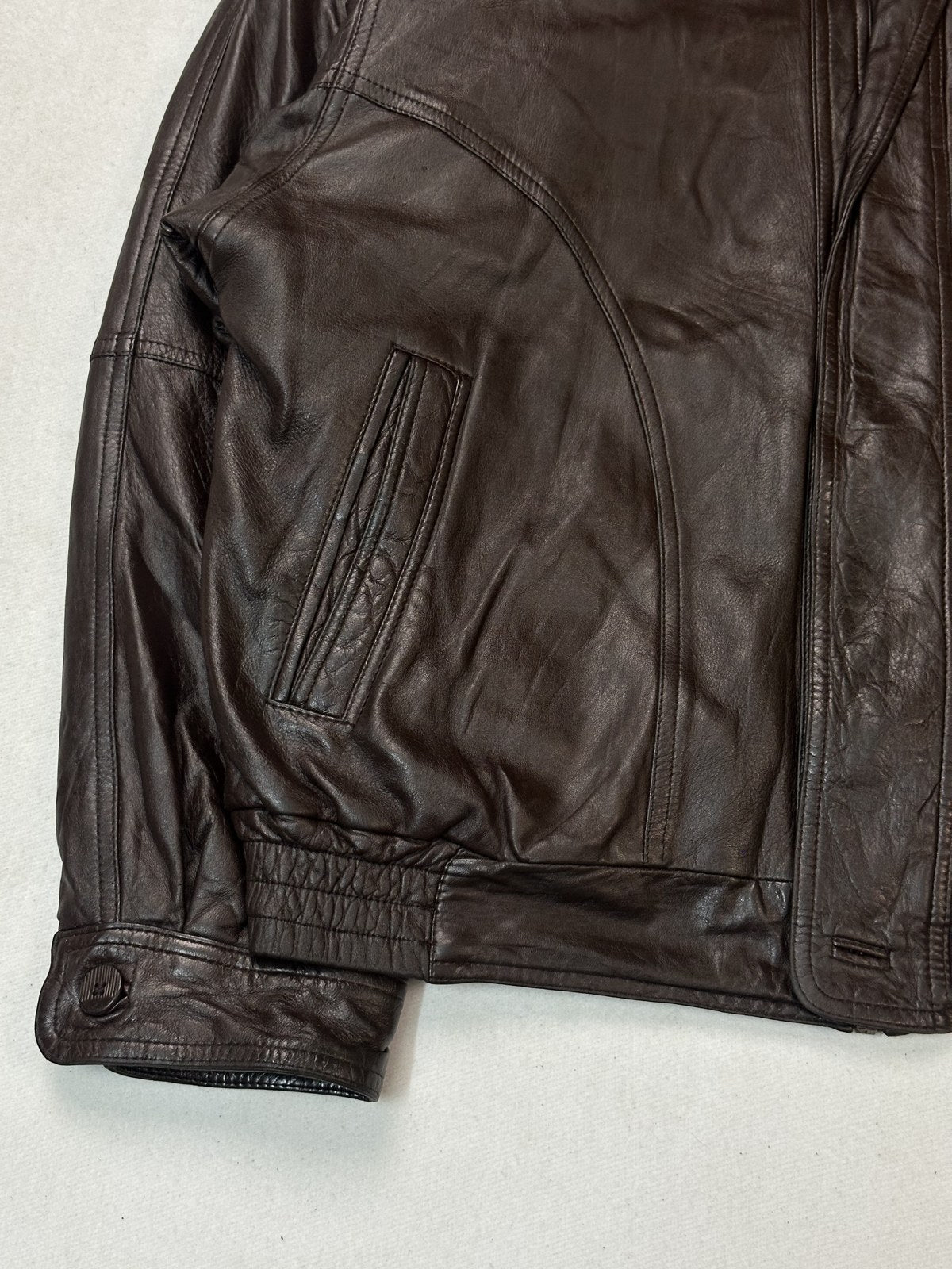 Shirt collar of the burgundy flight jacket, seen close enough to read the leather grain
