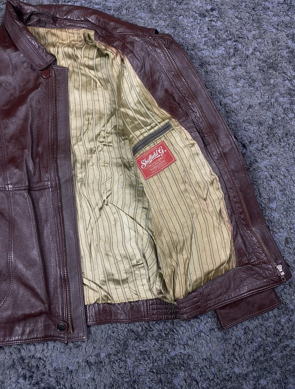 Shirt collar and zip pull on the burgundy leather flight jacket