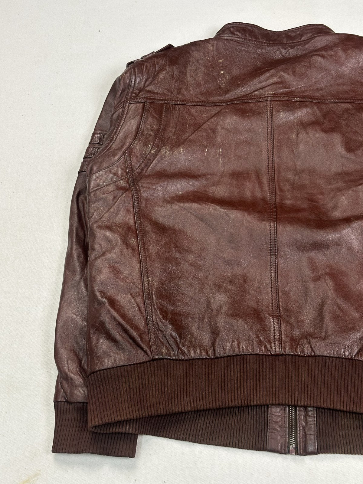 Close view of the knitted rib hem meeting the burgundy leather