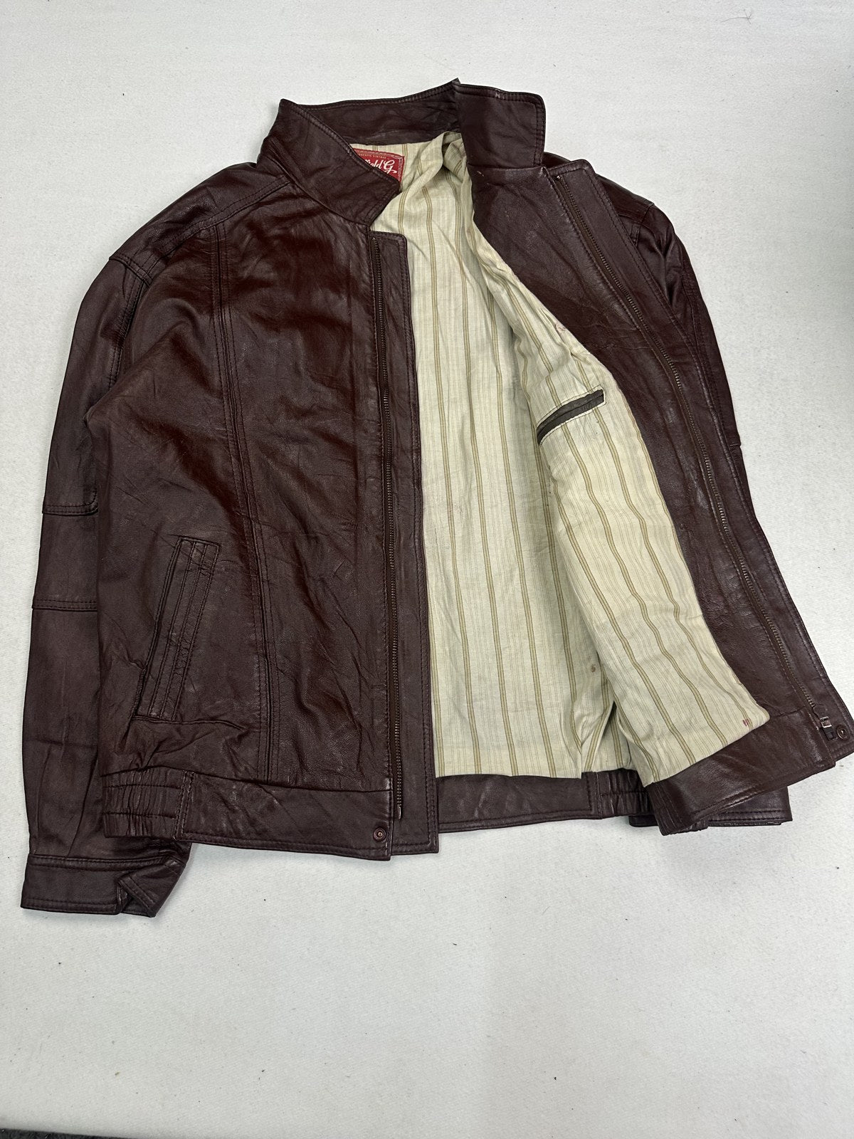 Ticking stripe lining revealed inside the burgundy flight jacket