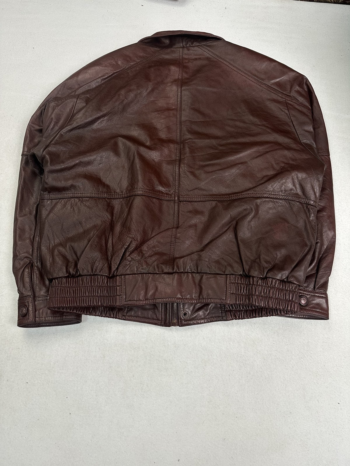 Rear view of the XL burgundy flight jacket showing the back panel above the rib hem