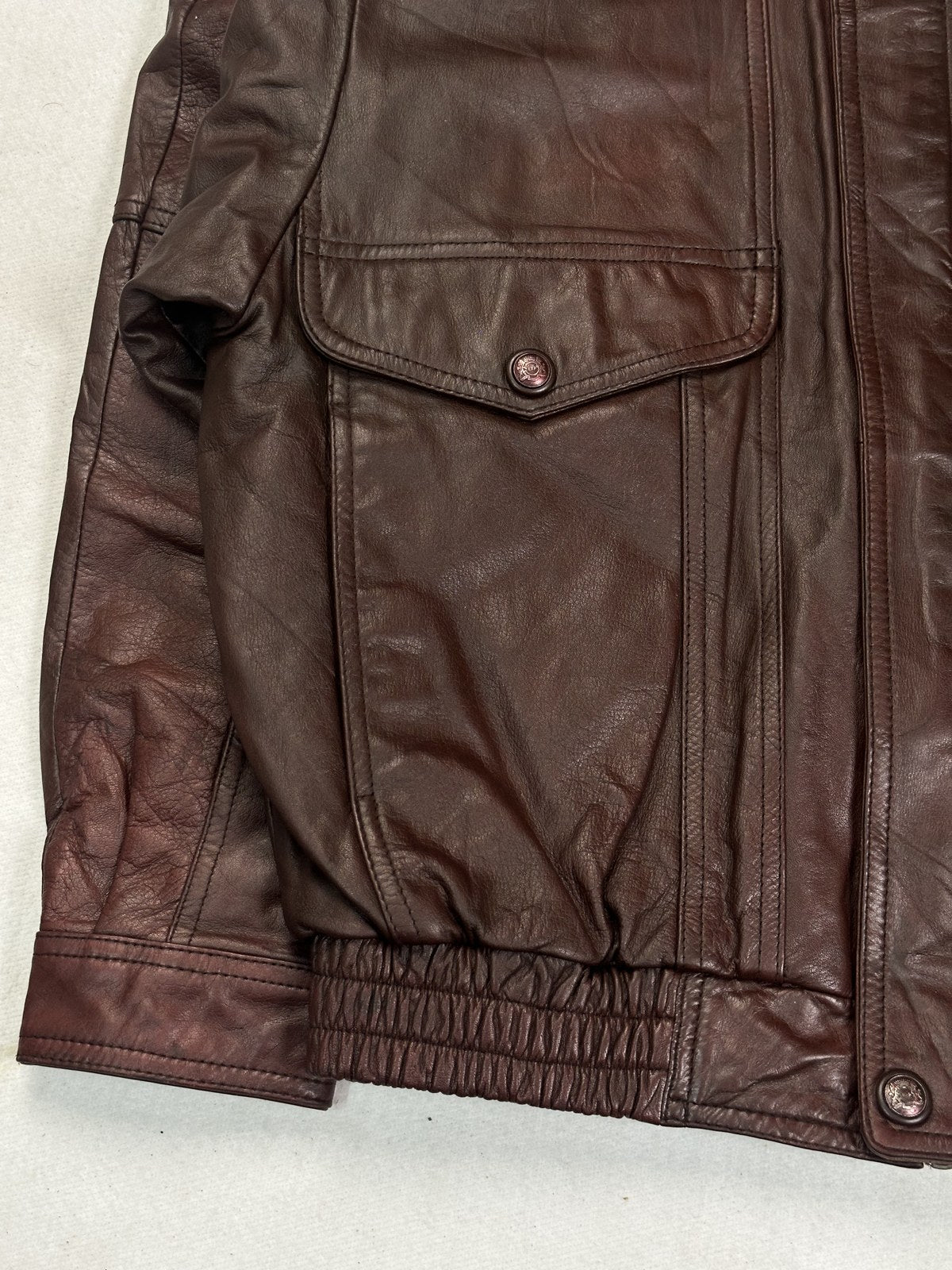 Collar and upper chest of the burgundy leather flight jacket seen close up