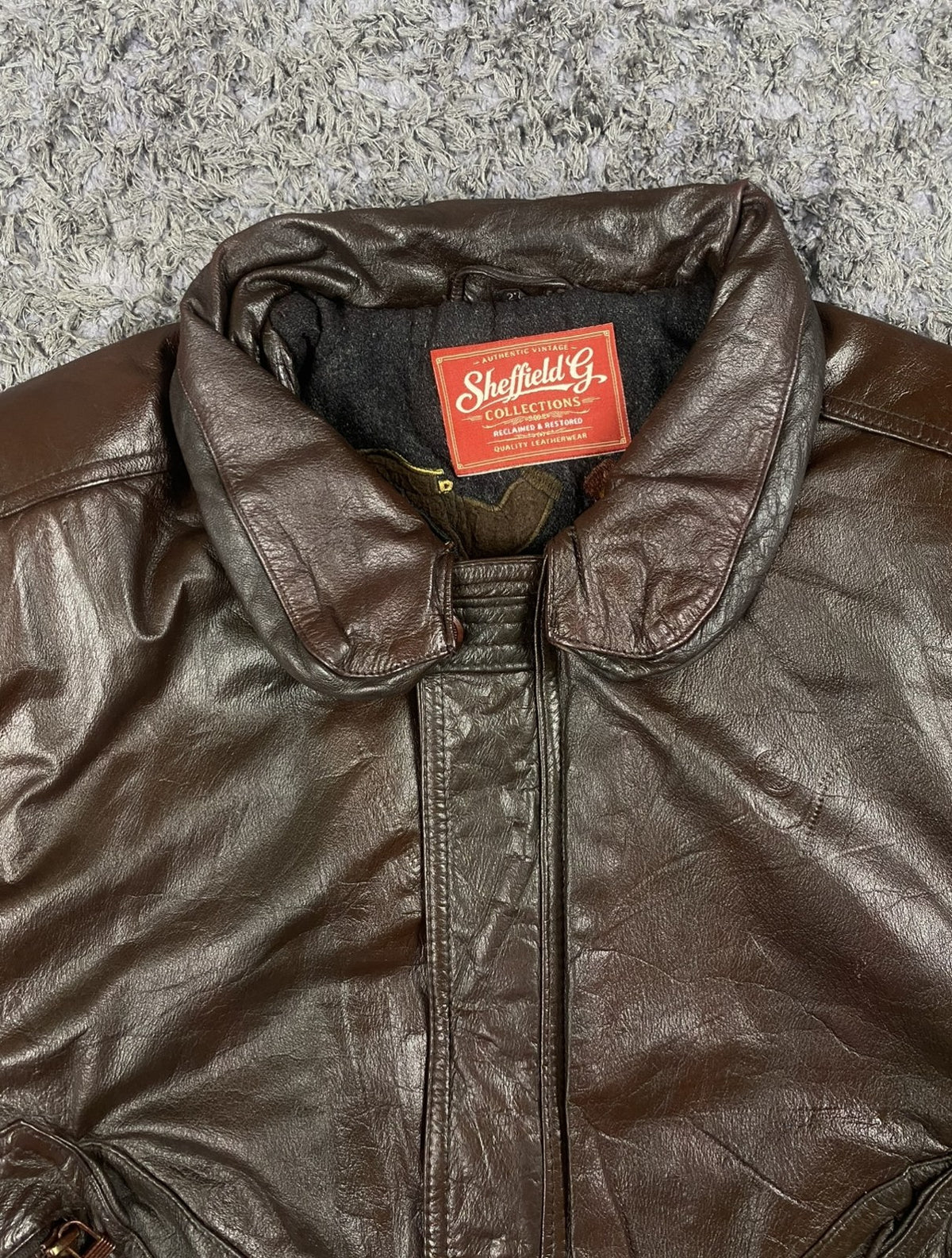 Wide shirt collar opened out on the burgundy leather flight jacket
